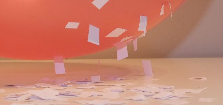 Naładowany balonik przyciągający skrawki papieru — elektryczność statyczna
